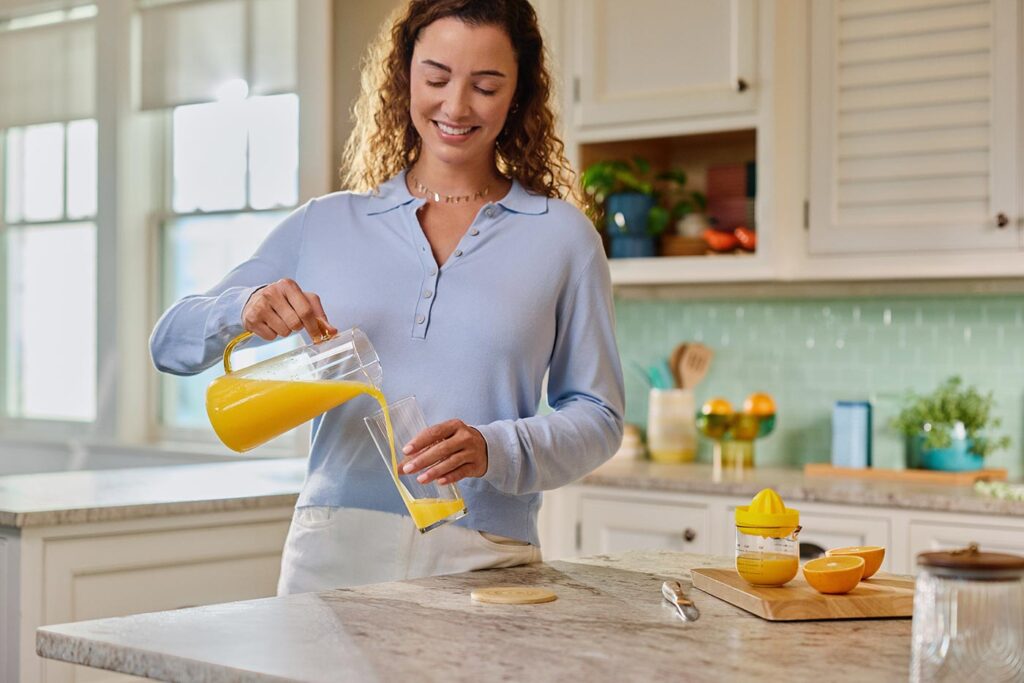 A woman pouring a glass of fresh Florida orange juice in her kitchen